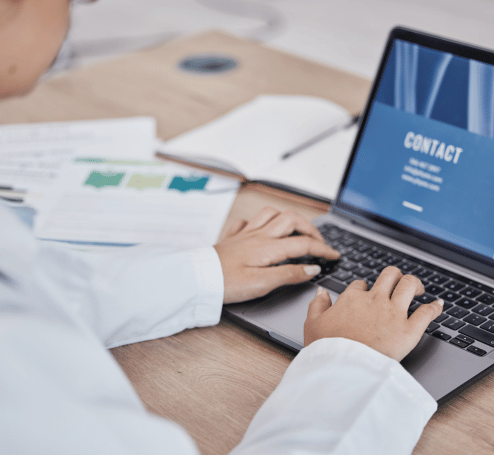 Professional typing on a laptop with the contact page open, symbolizing communication with Tria Medical Academy
